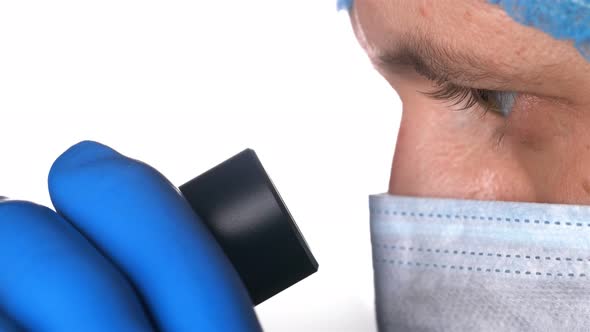 a Scientist Looks Through the Eyepiece of a Microscope