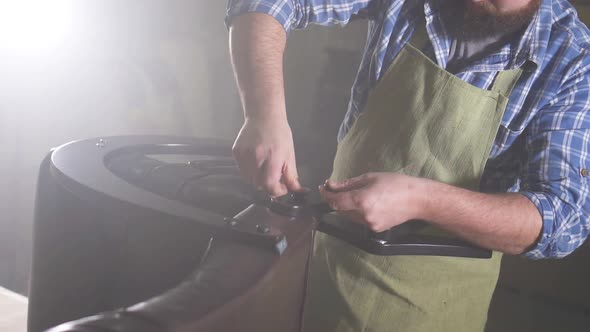 Hands of Male Master Assembling Furniture Closeup in a Dark Workshop Close Up