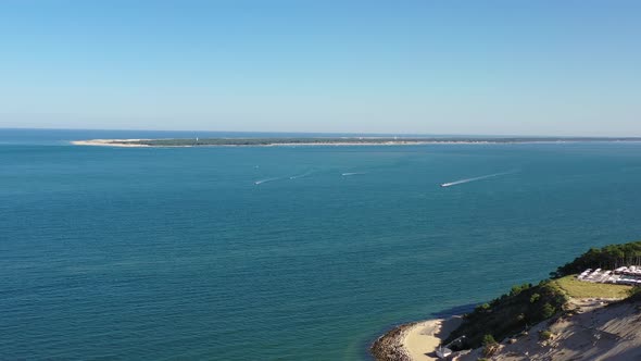 Motorboats headed to Dune du Pilat in Arcachon Bassin France from Cap Ferret seen in the background,