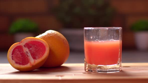 Close-up of Unrecognizable Man Throws Ice Cubes Into a Glass with Fresh Citrus Grapefruit Juice