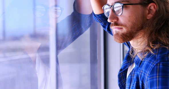 Male executive looking through window in office 4k