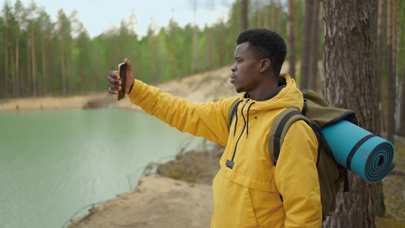 A Black Man is Walking on Top of a Mountain and Typing a Message and Photo on His Smartphone