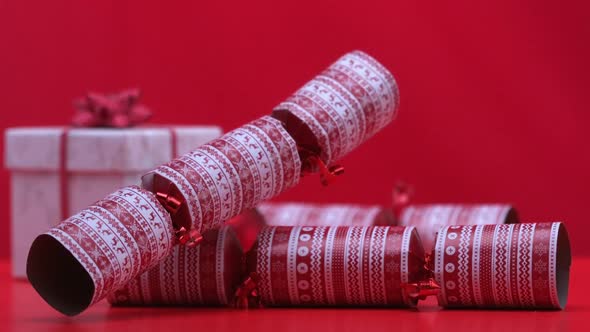 Christmas cracker dropping and bouncing beside present on red background