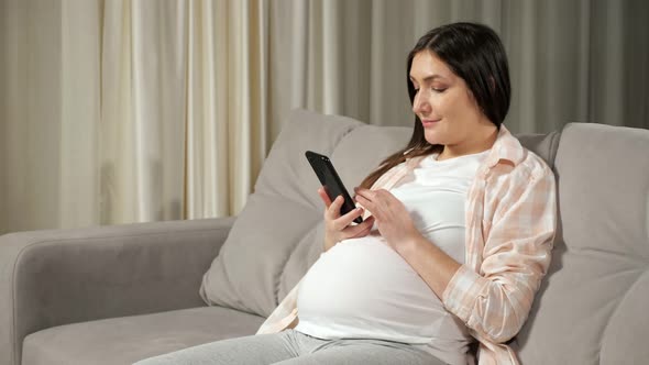 Pregnant Woman Scrolls Through Social Media Via Smartphone