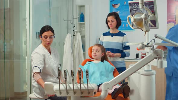 Stomatologist Doctor Explaining to Mother the Dental Process of Intervention