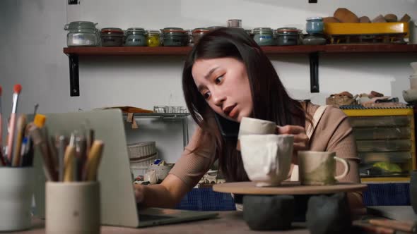 A young female ceramicist is busy checking orders for ceramics for a customer.