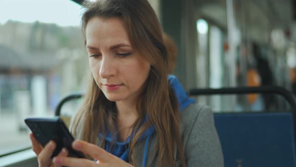 Woman in Tram Using Smartphone Chatting and Texting with Friends