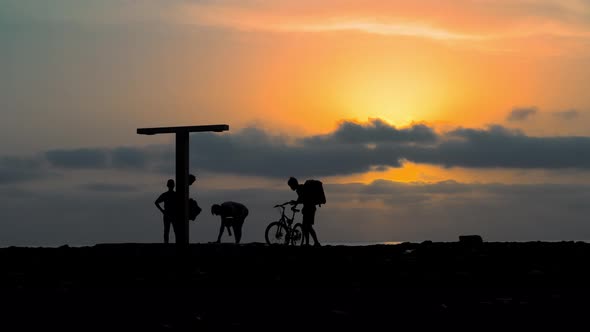 Silhouette of active young people playing volleyball against backdrop of sky by sea