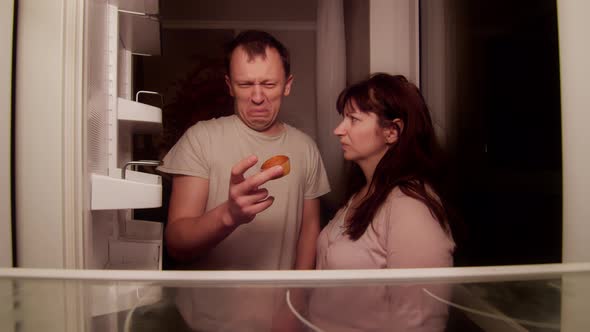 Married couple opens the refrigerator at night and finds there one spoiled cupcake