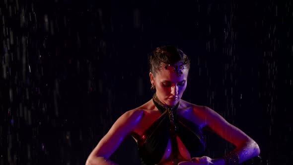 Closeup of a Woman Dancing an Oriental Dance on a Black Background in the Pouring Rain in the Studio