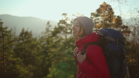 Slow Motion Portrait Young Woman in Red Jacket on Mountain Top at Sunset with Sun Raises and Flares