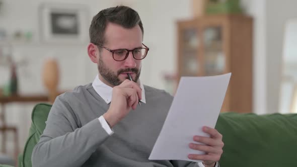 Middle Aged Man Reading Document and Making Notes