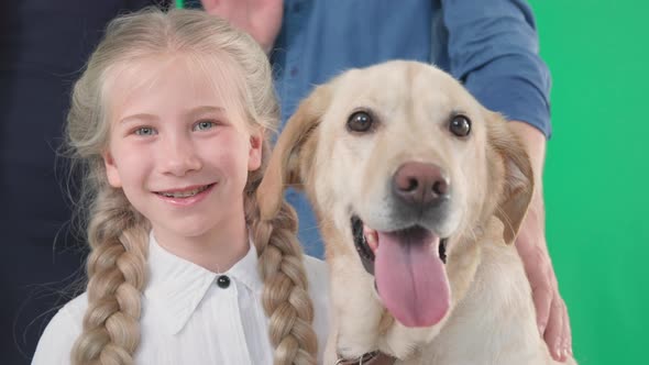 Portrait of Joyful Smiling Girl with Labrador Dog and Parents on Green Chrome Key Background Closeup