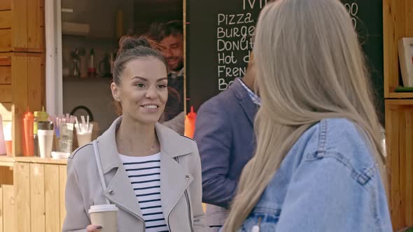 Smiling woman talking to her friend near coffee-shop