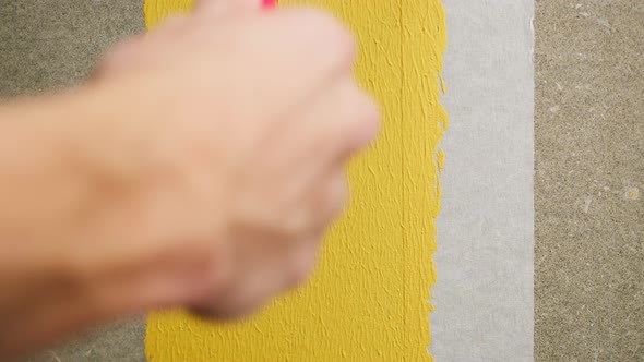 Painting Walls with Yellow Paint Using Roller Closeup