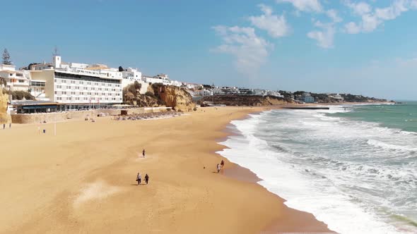 People strolling along pristine Albuferia sand beach, Algarve. Aerial forward