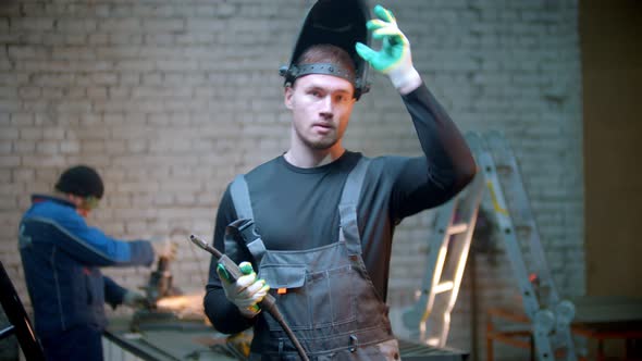 Young Handsome Man Standing in the Workshop Holding a Welding Instrument