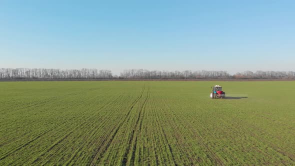Tractor Spreading Artificial Fertilizers in Green Field. Farmer Fertilizing Arable Land with