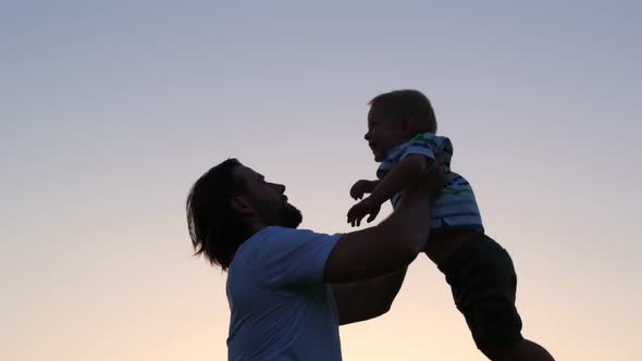 Father and son playing outdoor at the sunset time. Daddy and little baby son playing outside.