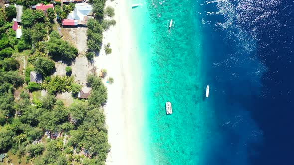 Luxury aerial tourism shot of a sandy white paradise beach and blue ocean background in vibrant 4K