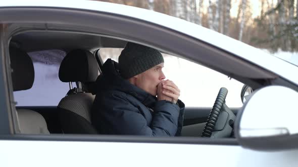 Man Blowing on His Hands Inside Car in Winter