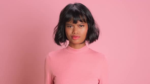 Dissatisfied Dark Skinned Woman Smirks Face and Says No on Pink Background