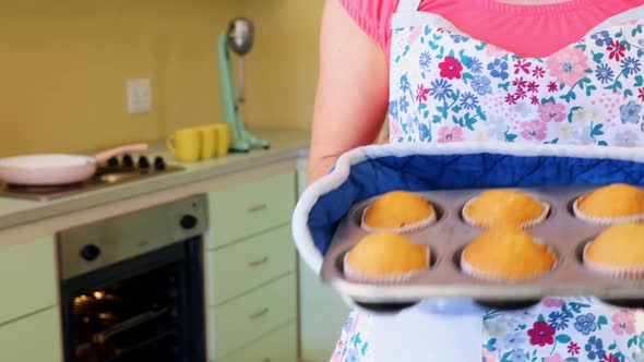 Waitress taking out muffins from oven 