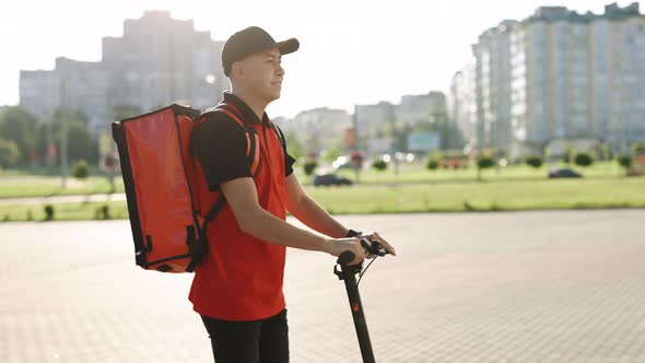 Male Deliverman Courier With Isothermal Backpack Case Pizza Box Rides His Electric Scooter