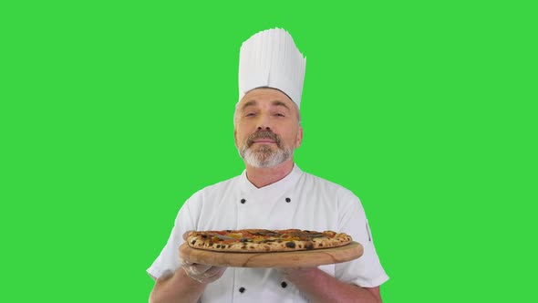 Smiling Chef Smelling Delicious Pizza and Doing Real Jam Gesture on a Green Screen, Chroma Key.