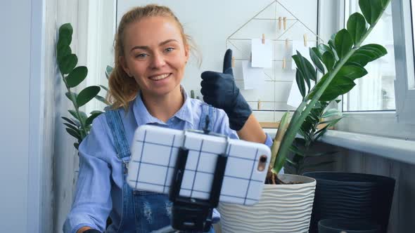 Gardener Woman Blogger Using Phone While Transplants Indoor Plants and Use a Shovel on Table