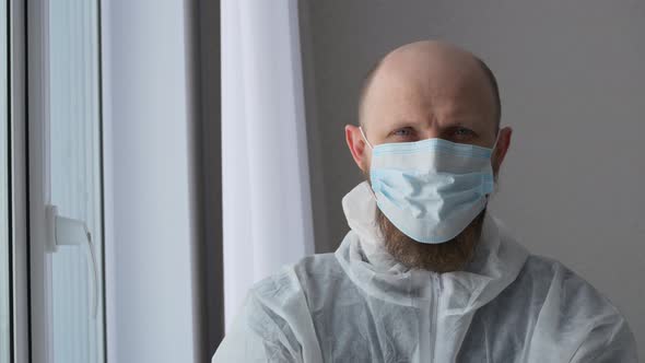 A Doctor in a Mask and Surgical Gown Looks at the Camera