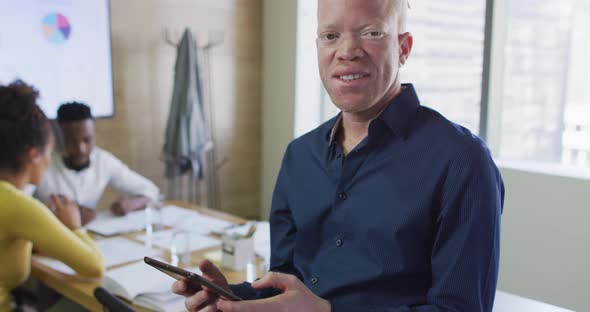 Portrait of happy albino african american businessman with tablet in creative office