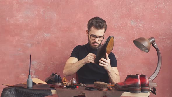 Young Man Checking the Glued Sole Beautiful Repaired Shoes in Man's Hands