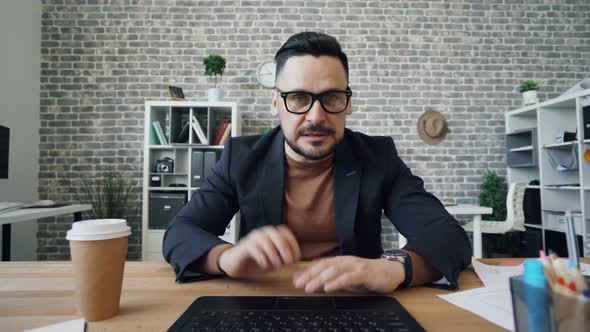 Bearded Man Talking Online Using Computer Looking at Camera Gesturing in Office