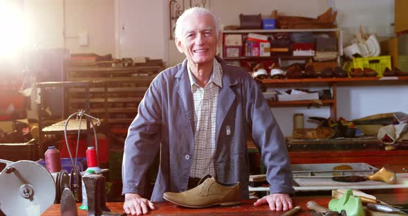 Portrait of smiling shoemaker standing in workshop