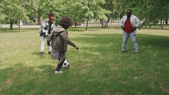 African-American Family of Three Playing Football Outdoors