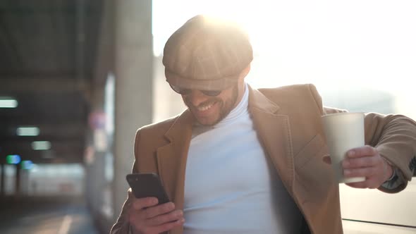 Always in Touch. Handsome Young Man Is Holding and Using Mobile Phone App. Bearded Businessman User