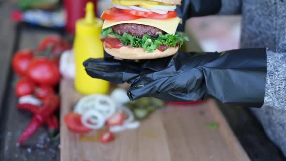 Close Up Shot Of A Female Hand Holding A Cheeseburger Outdoors