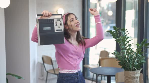 Cheerful Young Caucasian Slim Woman with Braces Turning on Vintage Tape Recorder Dancing in Slow