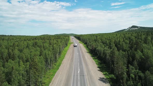 Aerial View of an Intercity Highway with Traffic Going Through a Green Forest on Bright Sunny Day