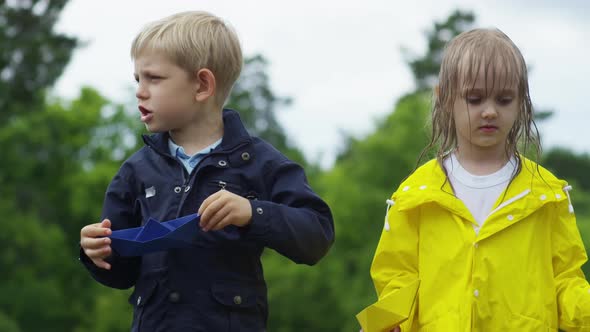 Children with Paper Boats Standing in Puddle