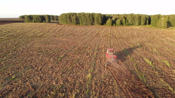 Red tractor cultivates the soil