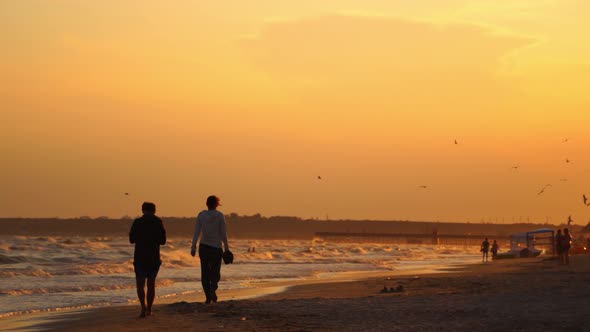 Colorful sea beach sunset. People walking during beautiful colorful sunset at the sea