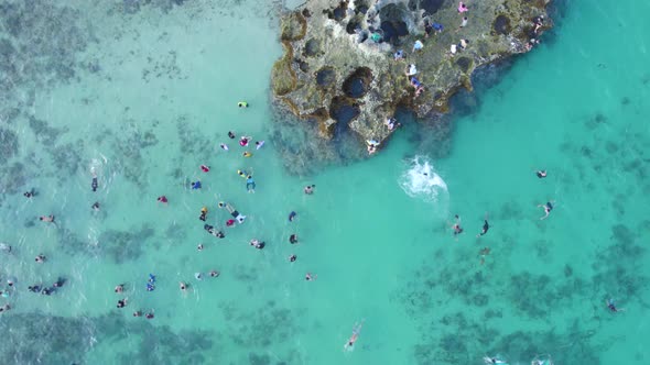 Aerial top down view of tourists enjoying a dip in shallow, turquoise and crystal clear waters of se