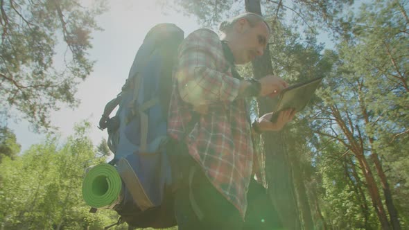 Mature Backpacker Man Choosing Best Path for Hiking Using Travel App on Tablet Pc