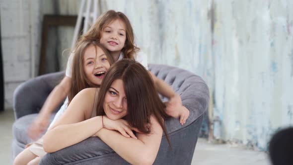 Mom Lies on the Couch and Cuddles with Her Daughters