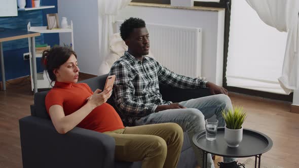 Interracial Parents Sitting in Living Room Expecting Child