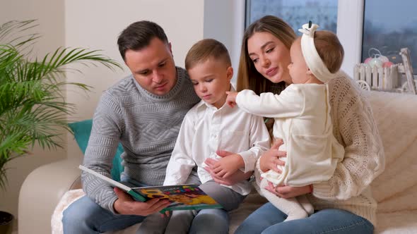 Adorable Family Father Reading a Book to Their Family Sitting in Living Room