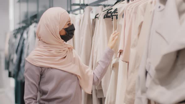 Young Muslim Woman in Protective Mask in Mall Chooses Outfit Buys Clothes at Discount Arab Girl