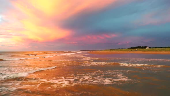 Sunset over ocean waves wash sand beach.